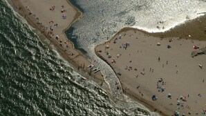 An aerial view of a beach with people, umbrellas, and a few boats. - Pleasant sea view apartment (Empuriabrava)