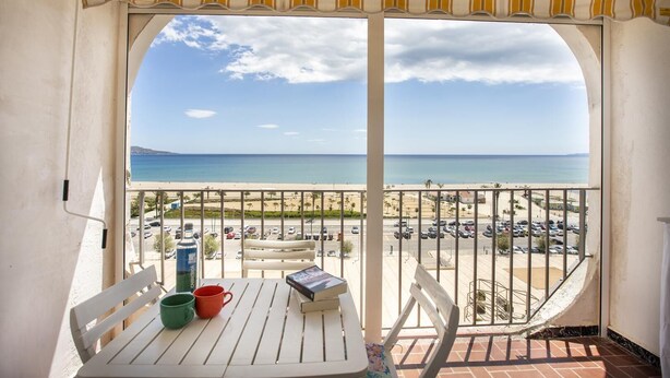 A balcony with a table, chairs, and a view of the beach and ocean. - Pleasant sea view apartment (Empuriabrava)