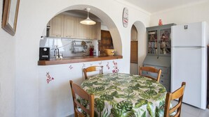 A compact kitchen with wooden cabinets, a built-in oven, and a refrigerator. There is a dining table with chairs and a decorative wall with butterfly decals. - Pleasant sea view apartment (Empuriabrava)