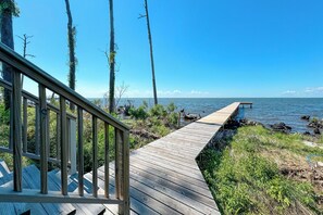 A wooden deck leading to a dock over water, surrounded by trees and vegetation. - Hideaway Bay - Private Pier & Sunsets Over Mobile Bay - Beachball Properties (Gulf Shores)