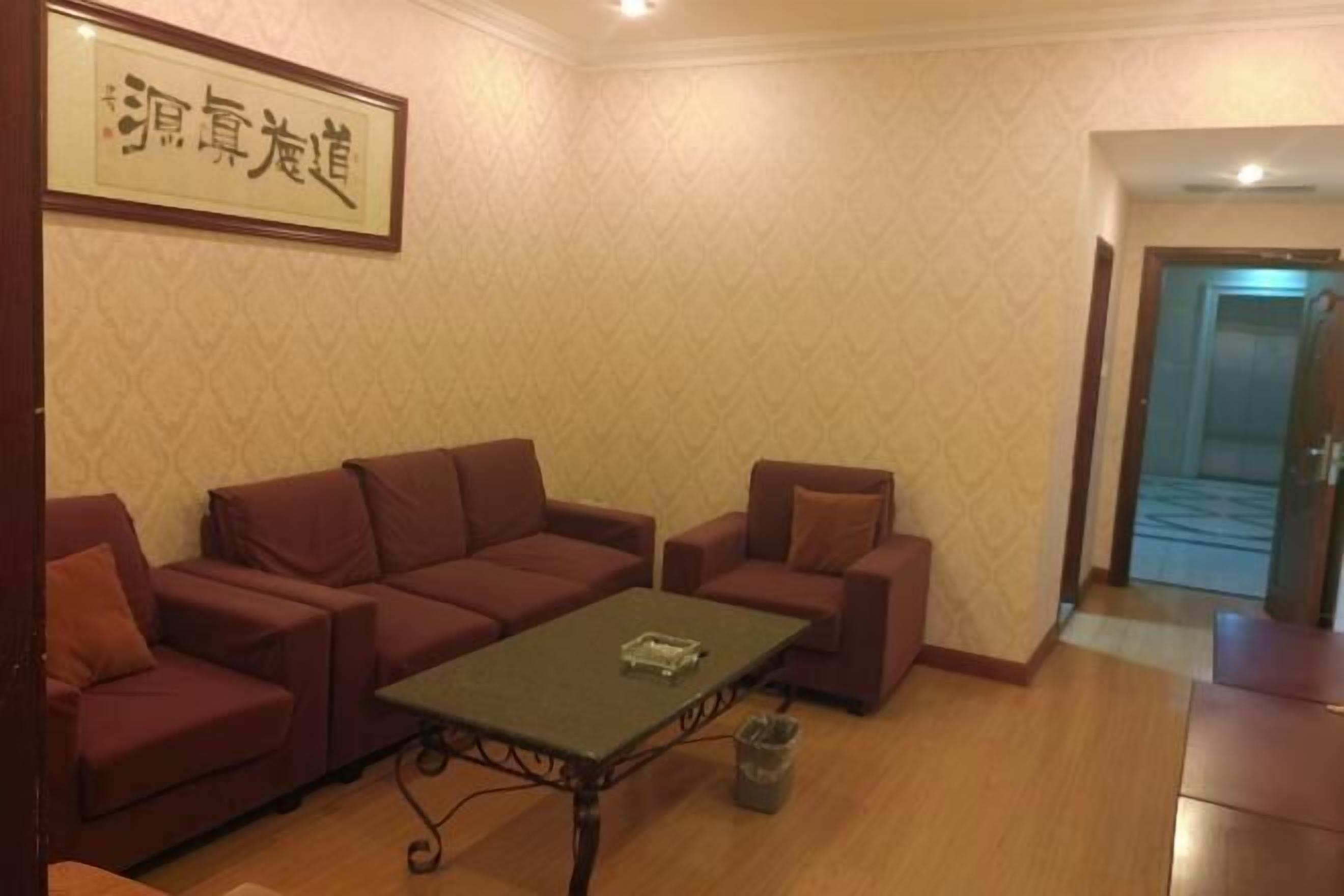 A room with a sofa set, a small table, and a trash bin.