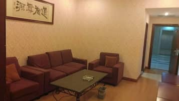 A room with a sofa set, a small table, and a trash bin.