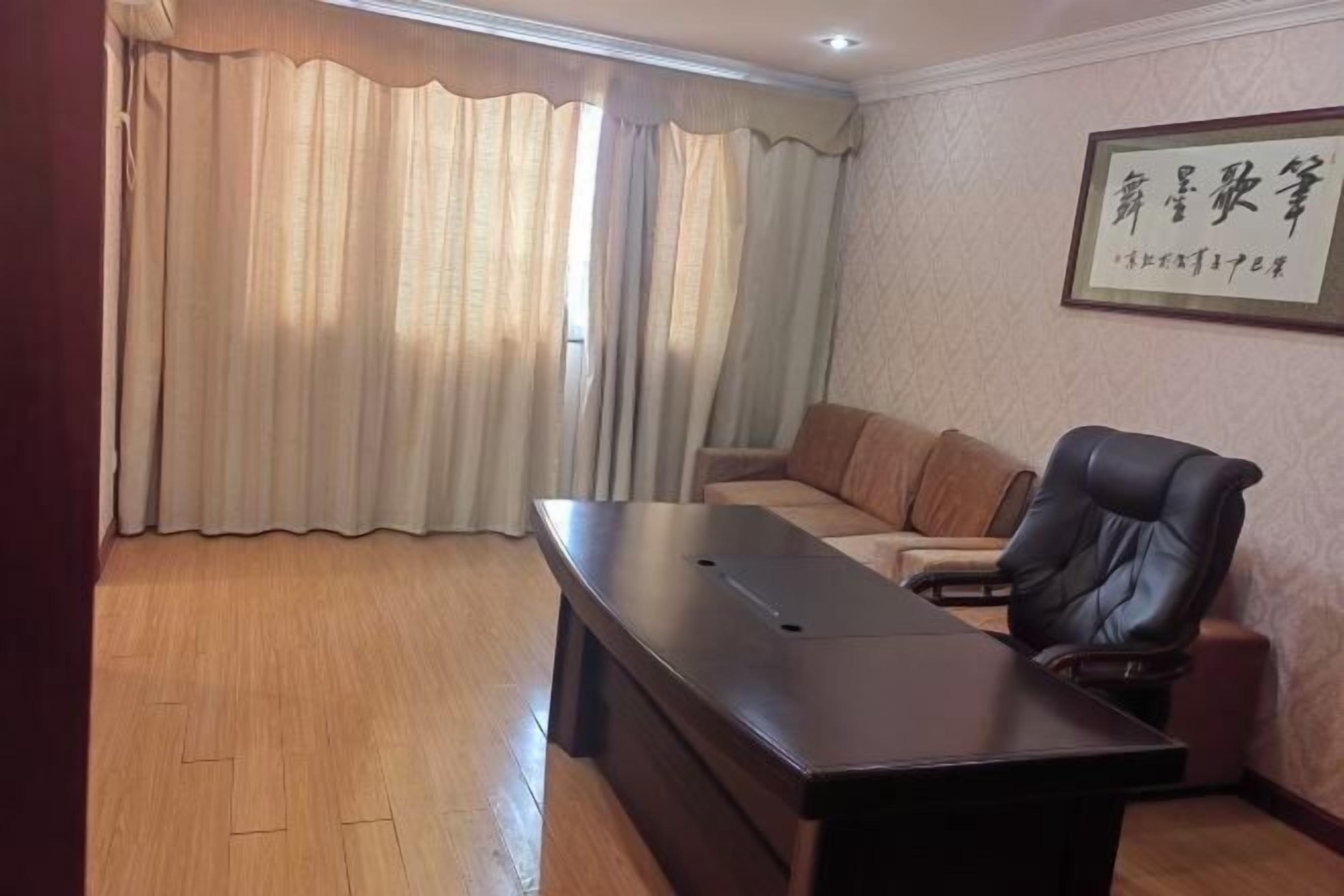 A conference room with a long table, leather sofa, and a black leather chair.