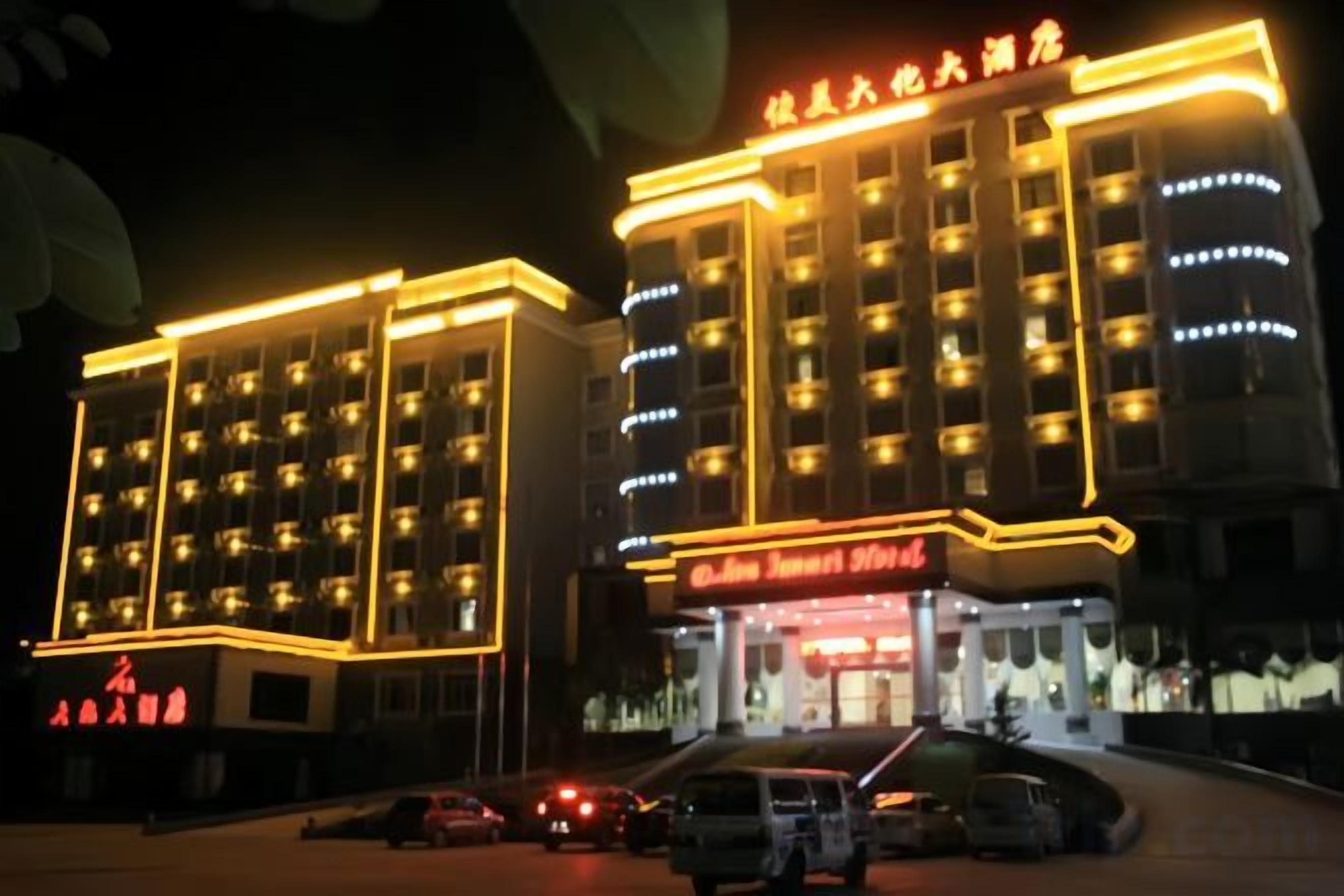 A multi-story hotel with illuminated signage and a parking area in front.