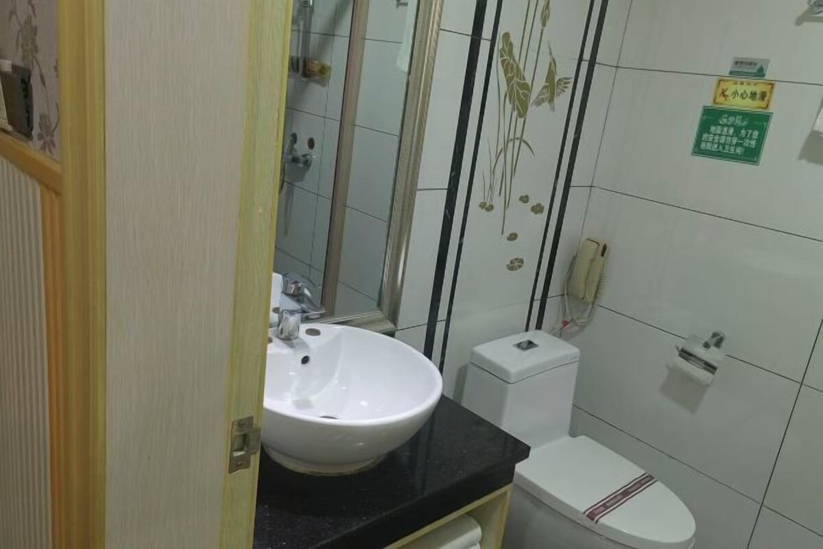 A bathroom with a white sink, toilet, and a shower area.