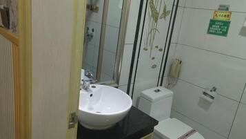 A bathroom with a white sink, toilet, and a shower area.