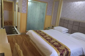 A hotel room with a bed, a wooden desk, a wardrobe, and a bathroom with a shower curtain.