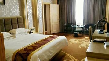 Una habitación de hotel con una cama grande, un escritorio, dos sillas y una puerta que da a otra habitación.