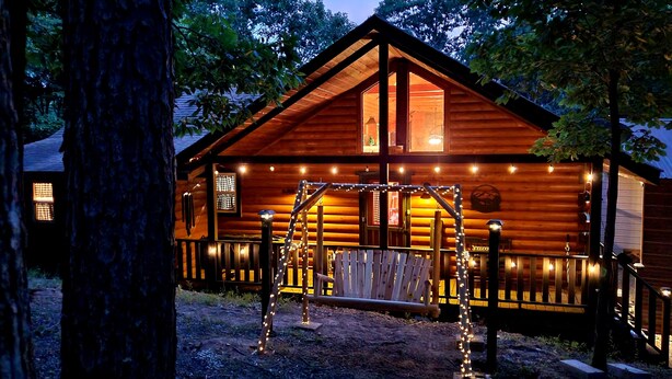 Una baita di legno con veranda, altalena e luci a stringa.