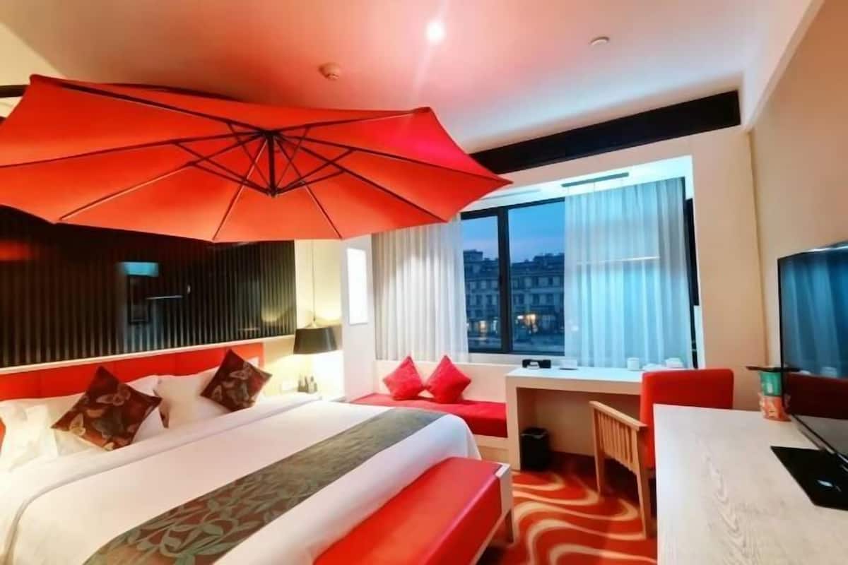 Een hotelkamer met een groot bed, een bureau en uitzicht op de stad.