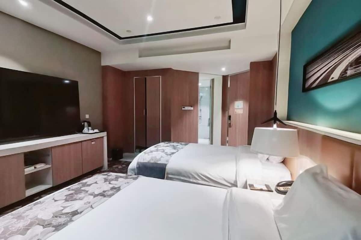 Een hotelkamer met twee bedden, een televisie, een bureau en een kledingkast.