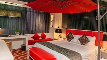 Ein Hotelzimmer mit Bett, Schreibtisch, Sitzbank, einem roten Regenschirm und einem Fernseher.