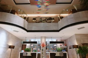 A modern hotel lobby with a curved ceiling, a central column, and a staircase. - Bingly Hotel (White Feather Road, Xixia, Nanyang) (Xixia)