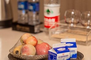 A table with a basket of apples, a carton of milk, and a bottle of water.
