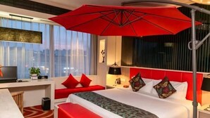 A hotel room with a bed, a desk, a red bench, a large window, and a red umbrella. - Bingly Hotel (White Feather Road, Xixia, Nanyang) (Xixia)