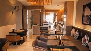 A modern restaurant with a long counter, cushioned seating, and a warm color scheme. - Bingly Hotel (White Feather Road, Xixia, Nanyang) (Xixia)