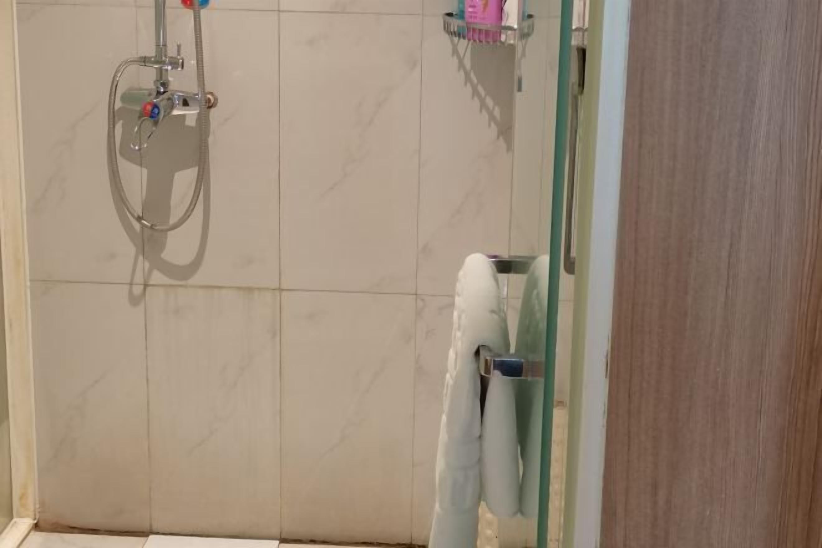 Un baño con ducha, un perchero y un estante con artículos de aseo.