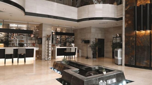 A modern lobby with a central water feature, a reception desk, and a seating area. - Bingly Hotel (White Feather Road, Xixia, Nanyang) (Xixia)
