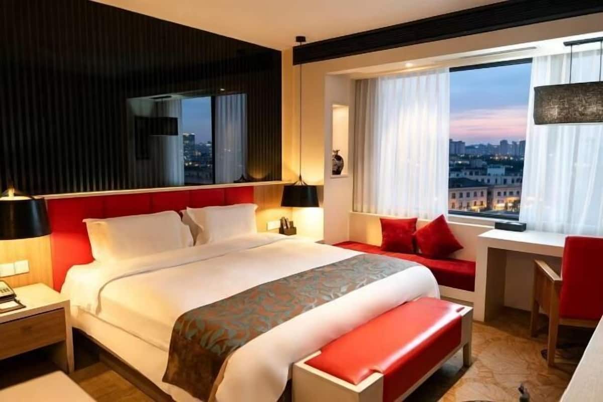 Een hotelkamer met een groot bed, een bureau, een stoel en uitzicht op de stad.