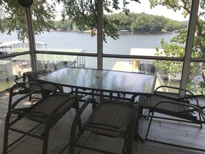 A glass-enclosed dining area with a view of a lake and docked boats.