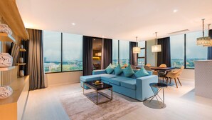 A modern living room with a blue sofa, a coffee table, and a dining area with chairs and a table. - EASTERN HOTEL BOJONEGORO (Bojonegoro)