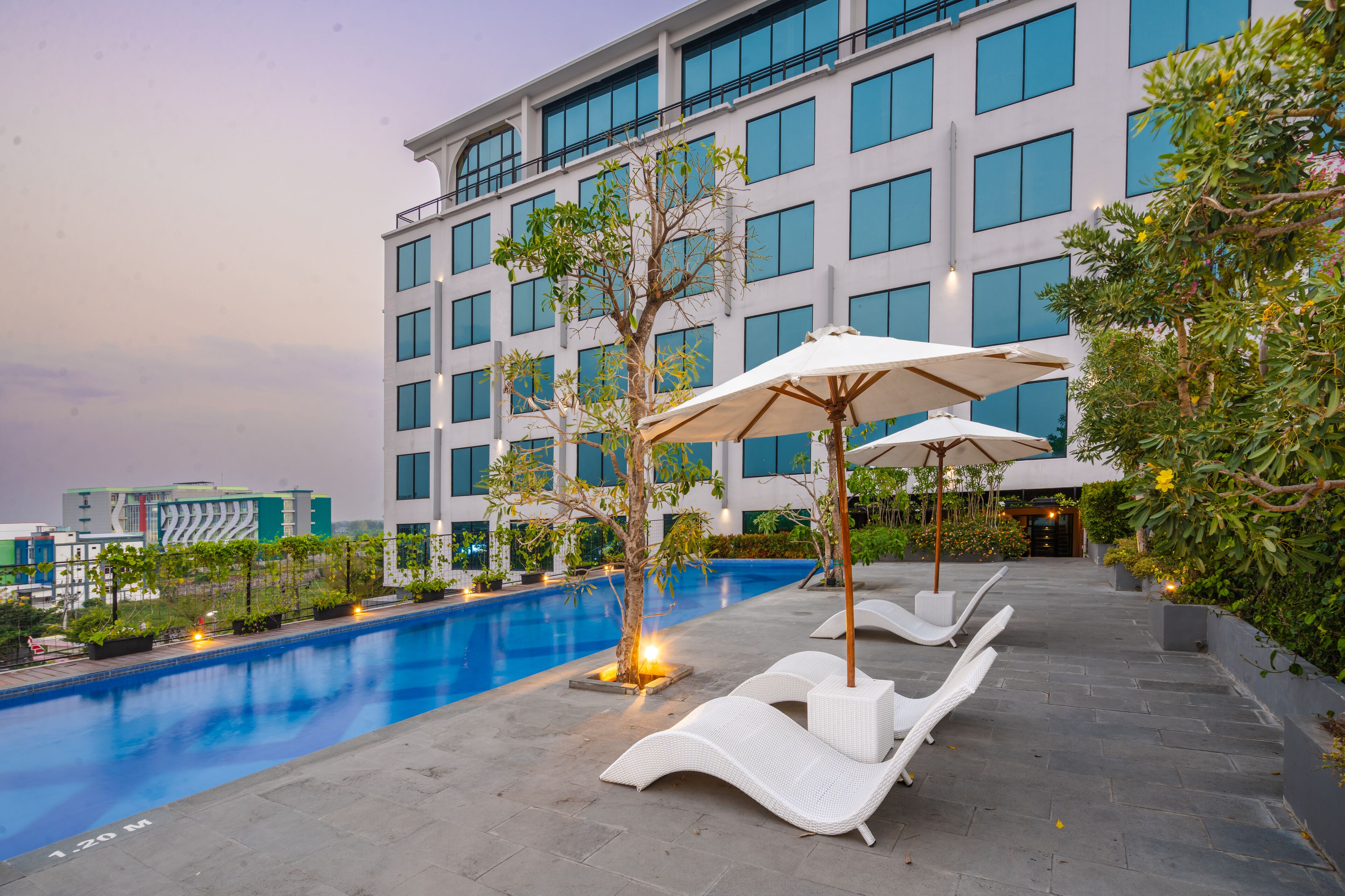A modern hotel with a swimming pool, lounge chairs, and umbrellas.