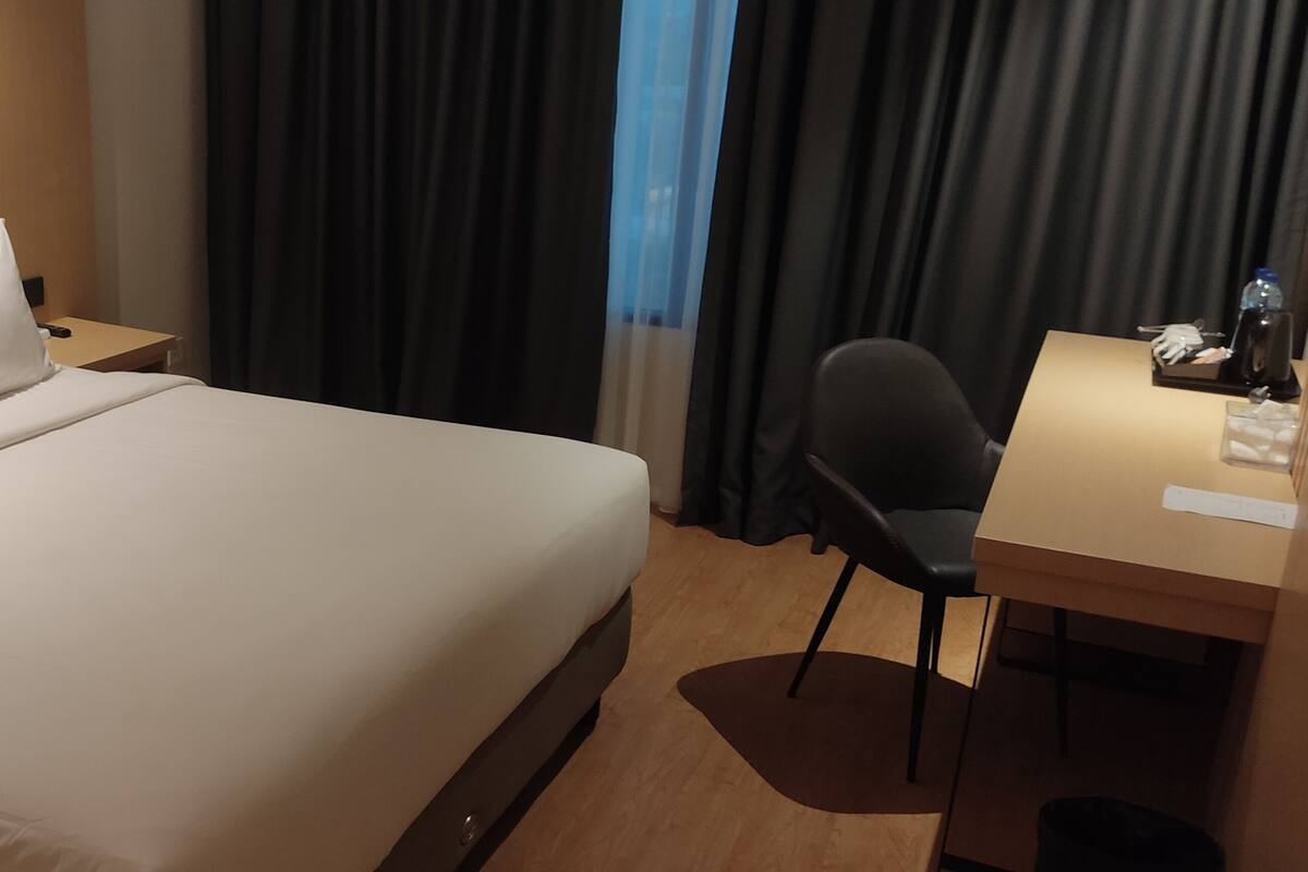 A hotel room with a bed, a desk, and a chair.