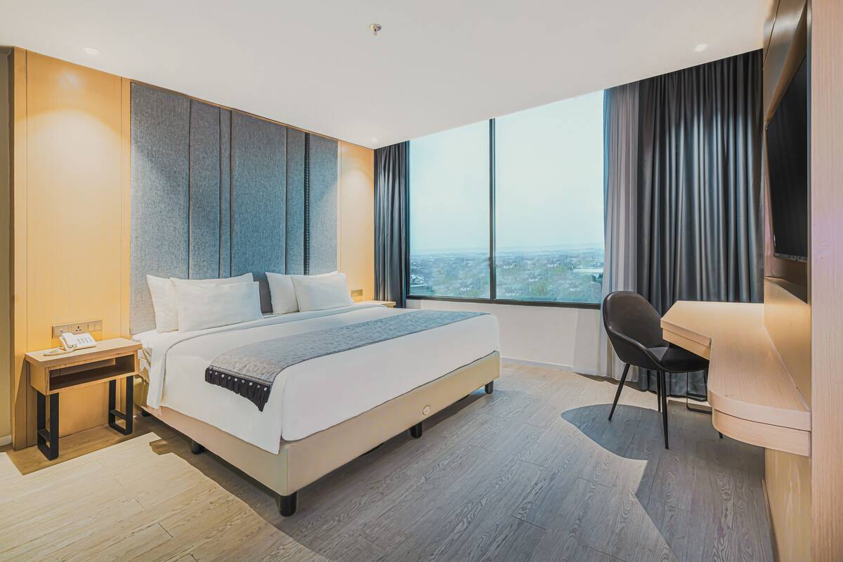 A modern hotel room with a large bed, a desk, and a chair.