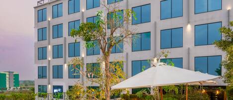 A modern hotel with a swimming pool, lounge chairs, and a well-lit outdoor area.