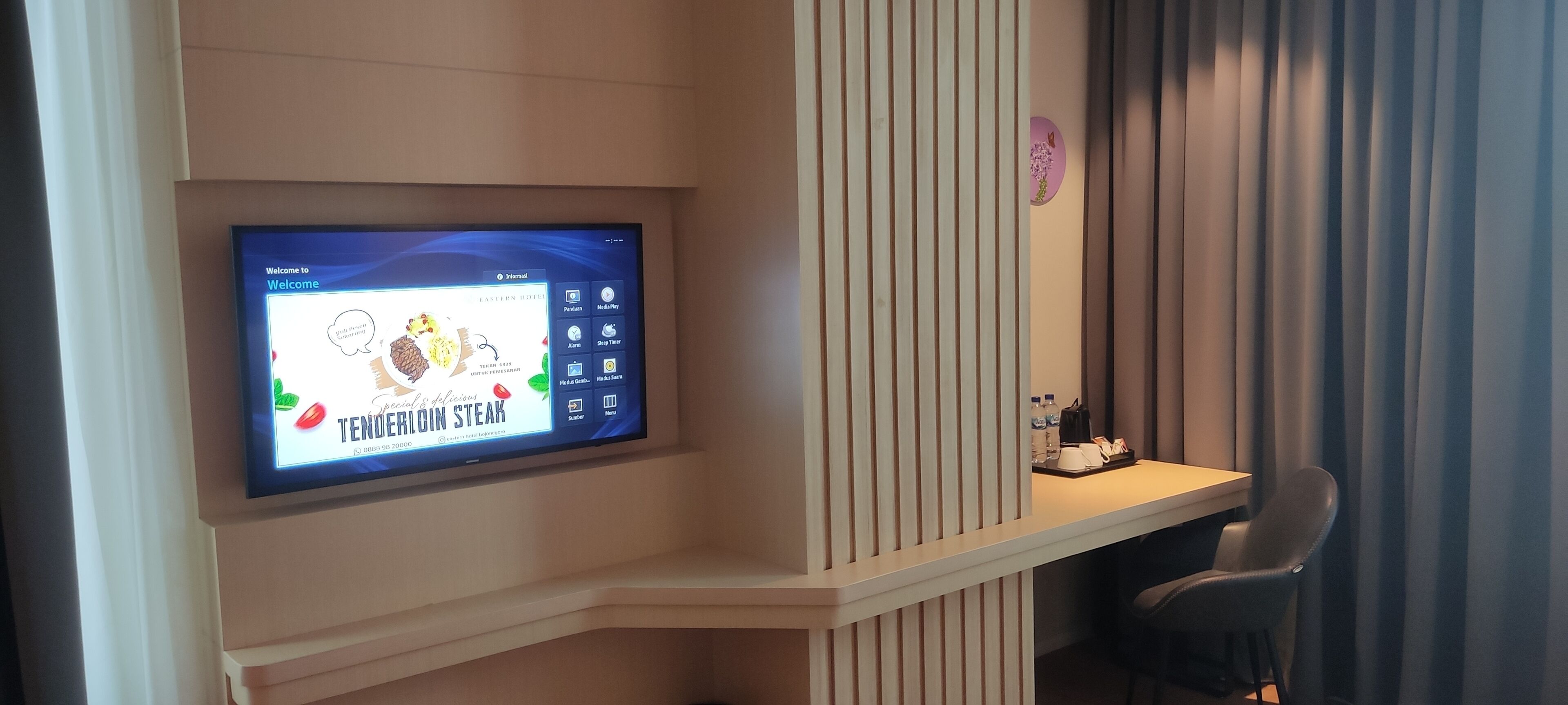 Un espace d’accueil d’hôtel doté d’un écran numérique affichant un message de bienvenue et les différentes options du menu.