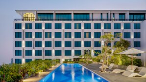 A modern hotel with a large pool, multiple balconies, and outdoor seating areas. - EASTERN HOTEL BOJONEGORO (Bojonegoro)