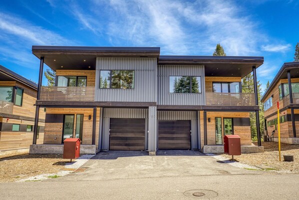 Un immeuble résidentiel moderne à deux étages, doté d  ’un garage, de grandes fenêtres et d’une allée bien entretenue.