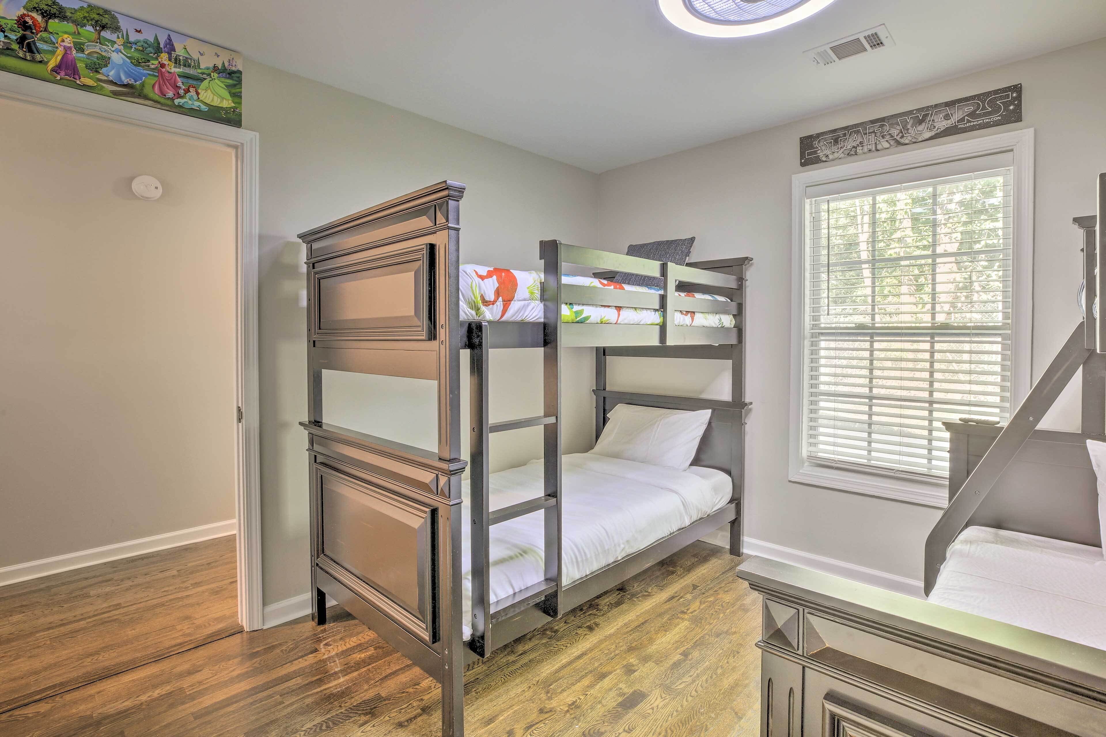 A bunk bed room with a Star Wars sign, a wooden floor, and a window with blinds.