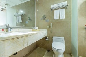 Une salle de bain avec un lavabo en marbre, des toilettes, un espace douche et un miroir.