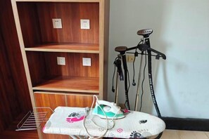 Een kamer met een houten schap, een strijkplank met een patroon en een fiets aan een standaard.
