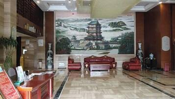 A hotel lobby with a reception desk, seating area, and a mural of a traditional building.