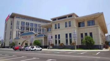 A multi-story building with a flat roof, large windows, and a parking lot in front.