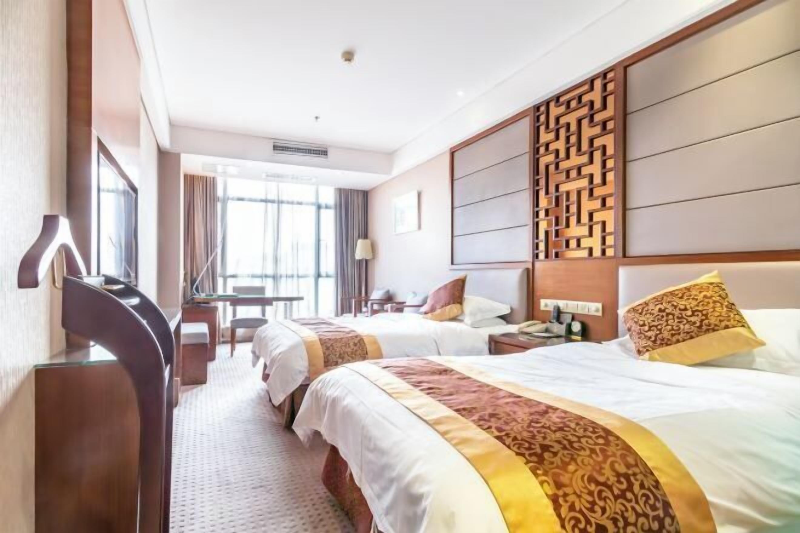 Ein Hotelzimmer mit zwei Betten, einem Schreibtisch und einem Stuhl.