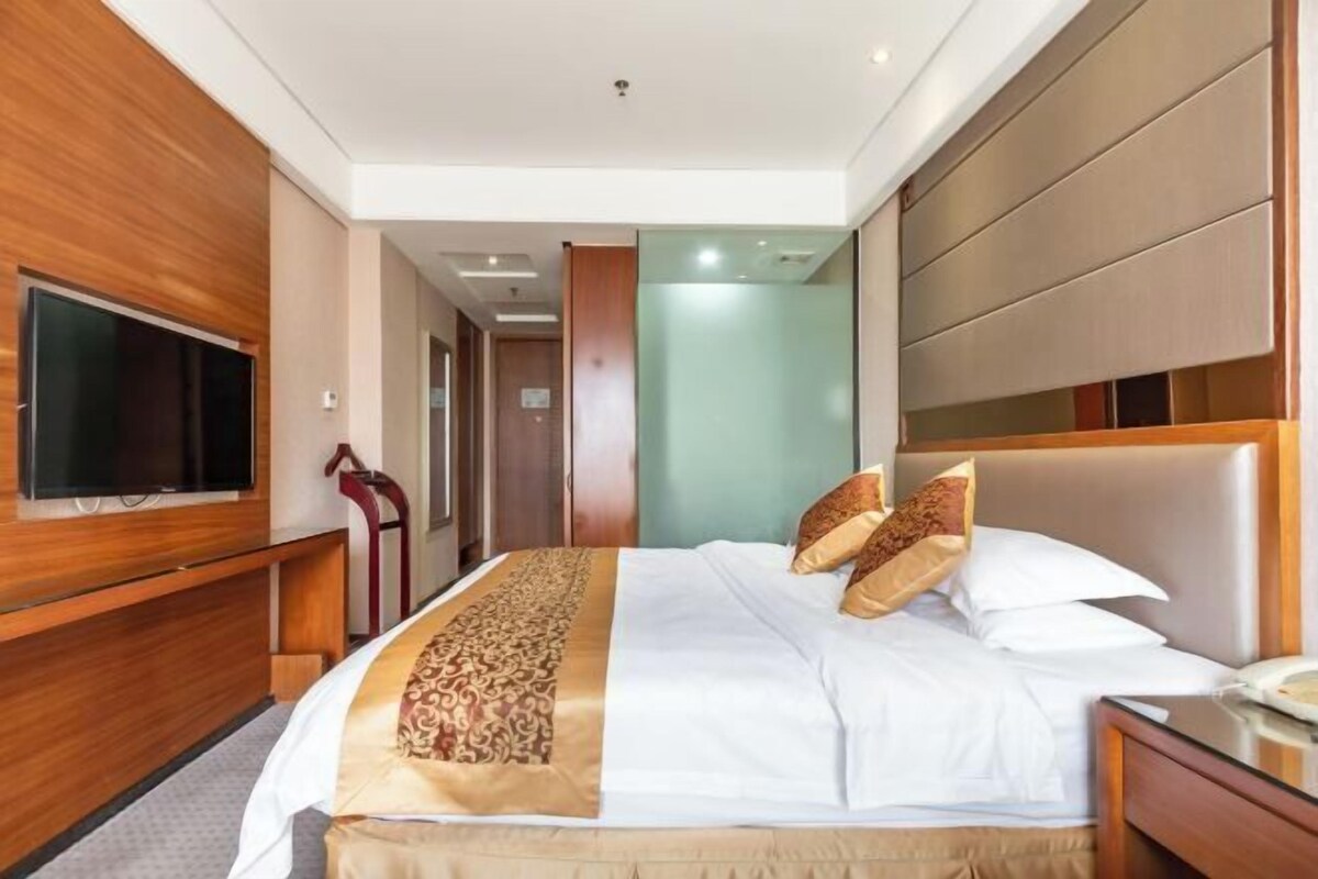 A hotel room with a bed, a television, and a wooden panel wall.