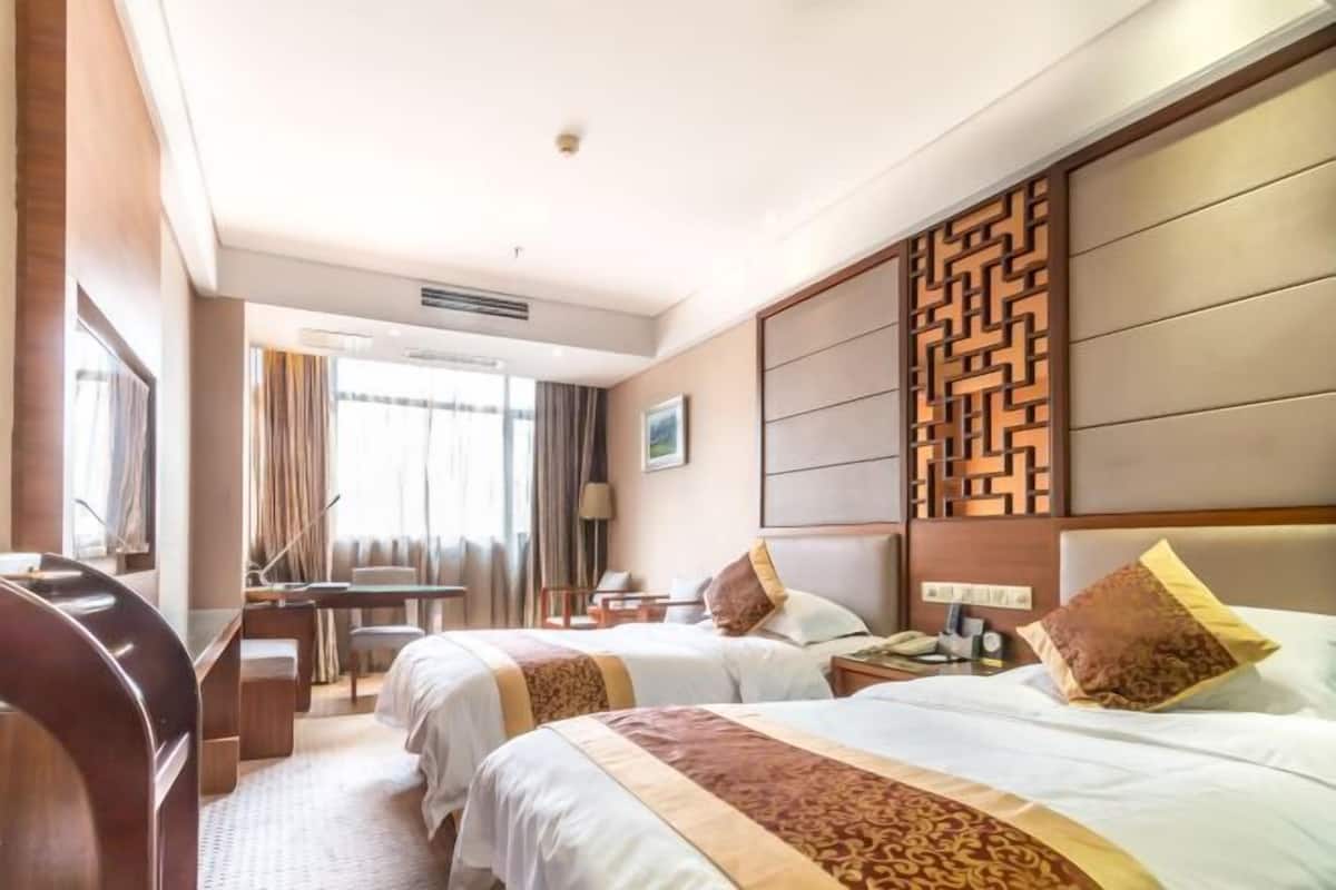 A hotel room with two beds, a desk, and a seating area.
