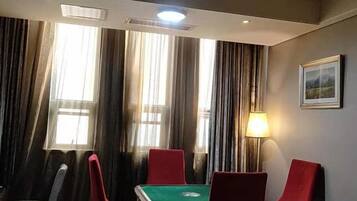 A room with a green table, red chairs, a lamp, and a framed picture on the wall.