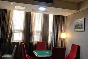 Une pièce avec une table verte, des chaises rouges, une lampe et un tableau encadré accroché au mur.