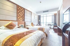 Une chambre d’hôtel avec deux lits, une télévision, un bureau et une grande fenêtre.