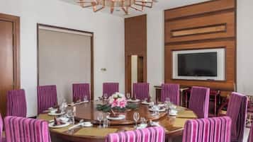A conference room with a round table, chairs, and a television screen.