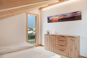 Une pièce avec un plafond en bois, une grande fenêtre, un meuble en bois et un tableau accroché au mur.