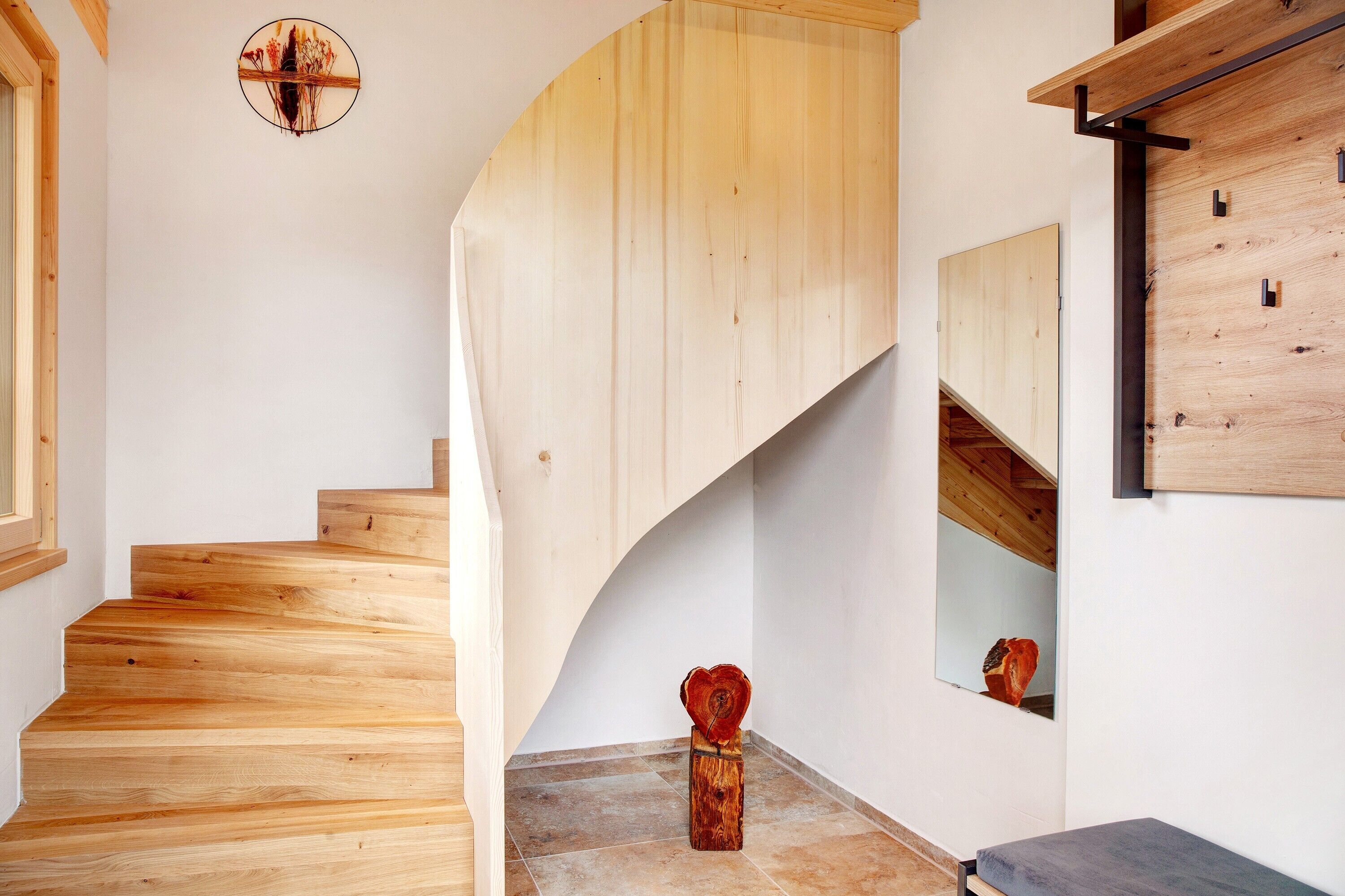 Eine hölzerne Treppe mit geschwungener Form, eine Holzvertäfelung und eine kleine Holzskulptur auf dem Boden.