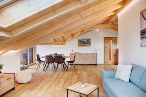 Une chambre moderne de style loft, comprenant un coin repas, un canapé, un plancher en bois et des poutres apparentes.