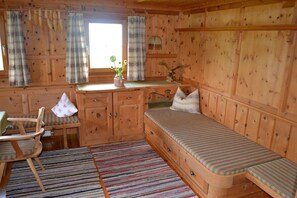 A wooden cabin interior with a bed, a chair, a small table, and a window with curtains. - 'Holiday Home Obersäuling' with Mountain View, Garden & Wi-Fi (Stummerberg)