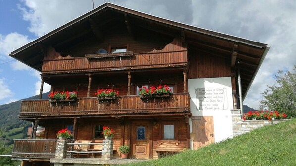 A wooden chalet with balconies, a stone staircase, and a signboard. - 'Holiday Home Obersäuling im Sommer' with Mountain View, Garden & Wi-Fi (Stummerberg)