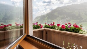 Un balcon doté de balustrades en bois et de jardinières contenant des fleurs roses et blanches.